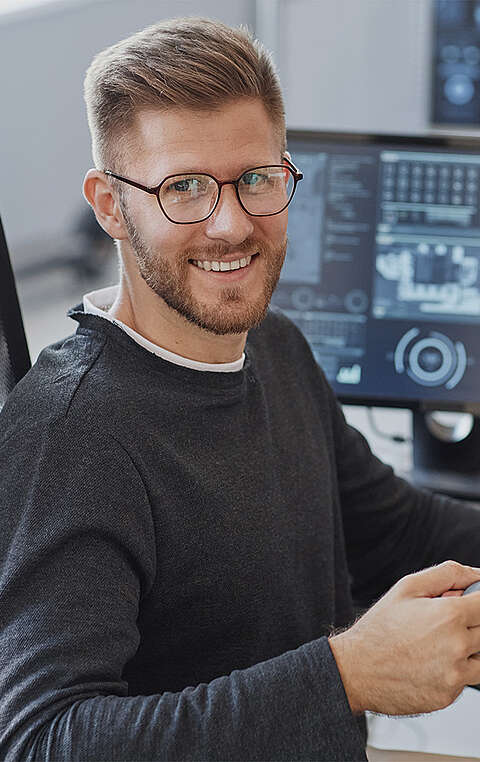  Mann sitzt an einem Schreibtisch und hält eine Tasse in der Hand 