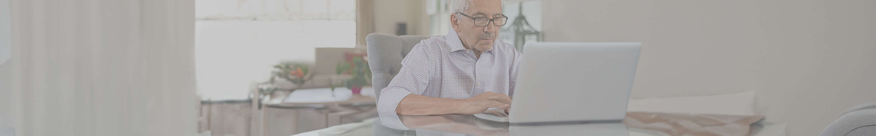 Älterer Mann sitzt vor einem Laptop
