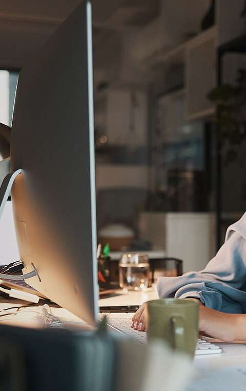 Frau sitzt am Laptop und lächelt in die Kamera