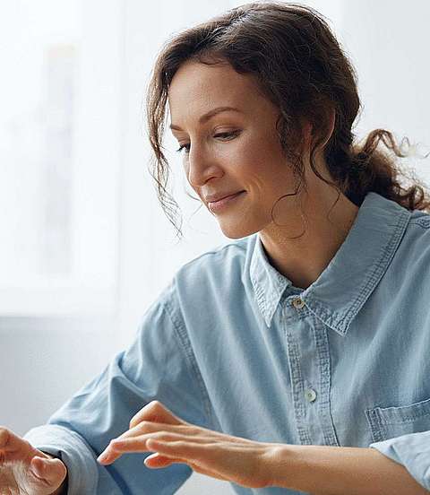 Frau sitzt vor Laptop und tippt etwas ein