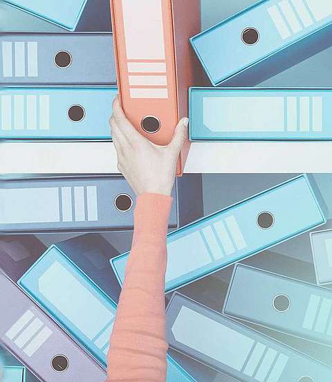 Hand zieht einen Ordner aus einem Schrank