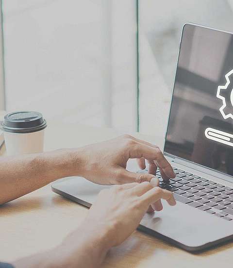  Mann sitzt am Schreibtisch vor einem Laptop 