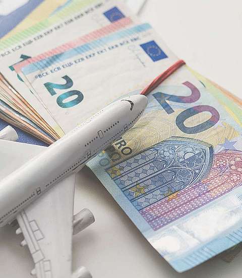  Reisepässe, Geldscheine und ein Spielzeug-Flugzeug liegen auf einem Tisch 