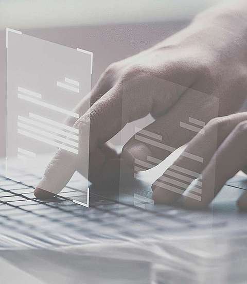 Person tippt auf die Tastaturen eines Laptops