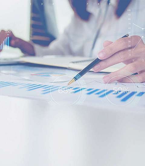  Frau sitzt vor einem Laptop, vor ihr liegt ein ausgedrucktes Diagrammblatt. 