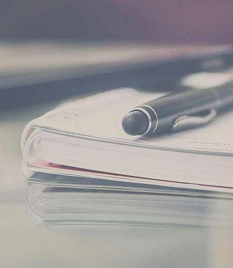 Kulli, Smartphone und Notizblock liegen auf einem Tisch